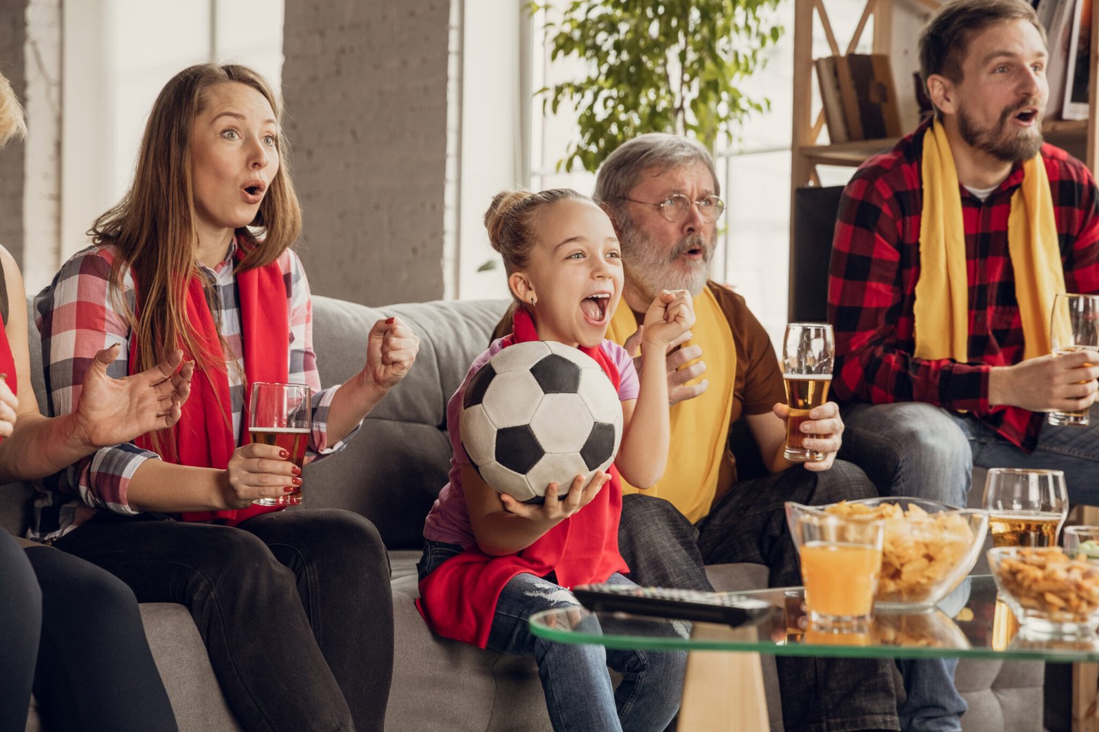 Excited, happy big family watching football, soccer match on the couch at home. Fans emotional cheering for favourite national team. Having fun from grandparent to children. Sport, TV, championship.